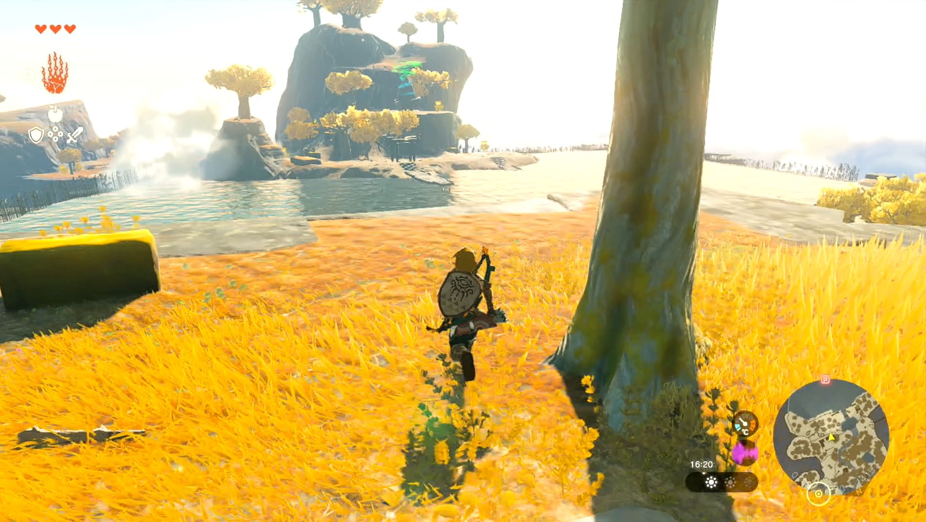 Link approaching the edge of a cliff that overlooks a lake, with the In-Isa Shrine on the other side.