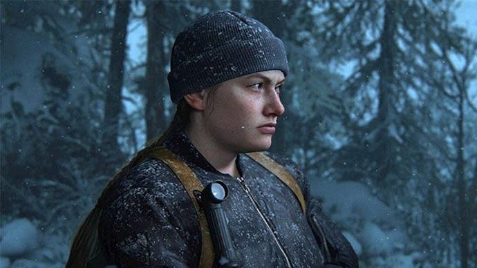 Abby in The Last of Us Part 2. She is wearing dark clothing, with a beanie hat and a backpack, and standing in a snowy woodland area