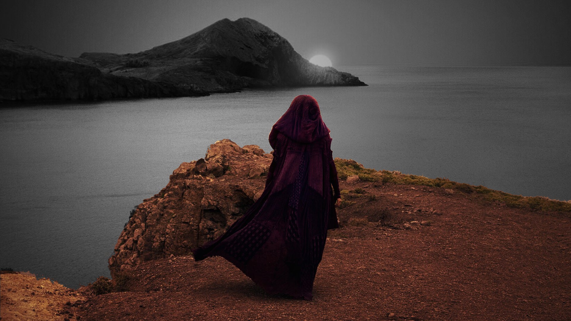 The Acolyte stands looking over a sandy sea, with the background in black and white and the foreground in colour. - 1