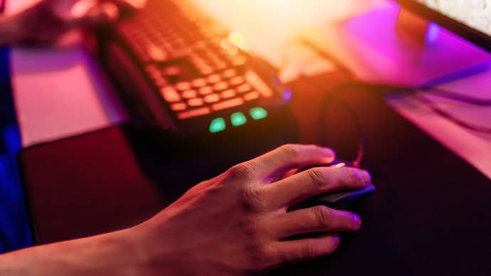 Close-up of someone’s hand on a mouse as their other hand rests on their keyboard in the background.