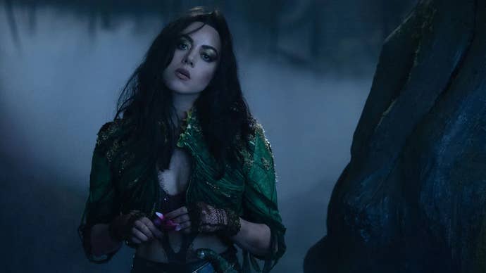 Aubrey Plaza as Rio Vidal in Agatha All Along, she looks curious about something, her head tilted, and she’s stood in some foggy woods.