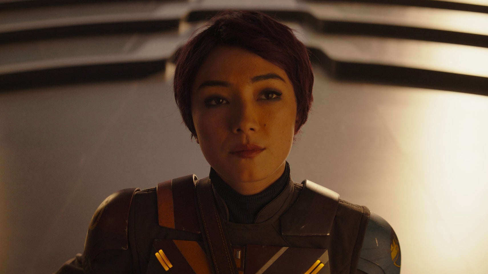 Sabine Wren in Ahsoka, she is stood with a plain expression on her face, her purple hair cut short. - 1