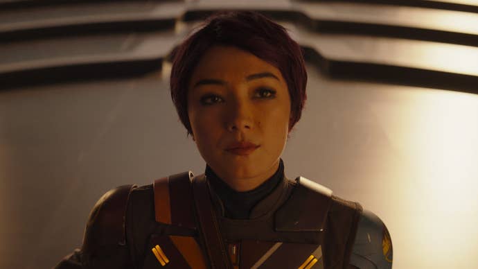 Sabine Wren in Ahsoka, she is stood with a plain expression on her face, her purple hair cut short.