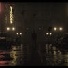 Alan Wake 2 concept art showing Alan standing at night in a wet city street, lit by neon liquor signs.