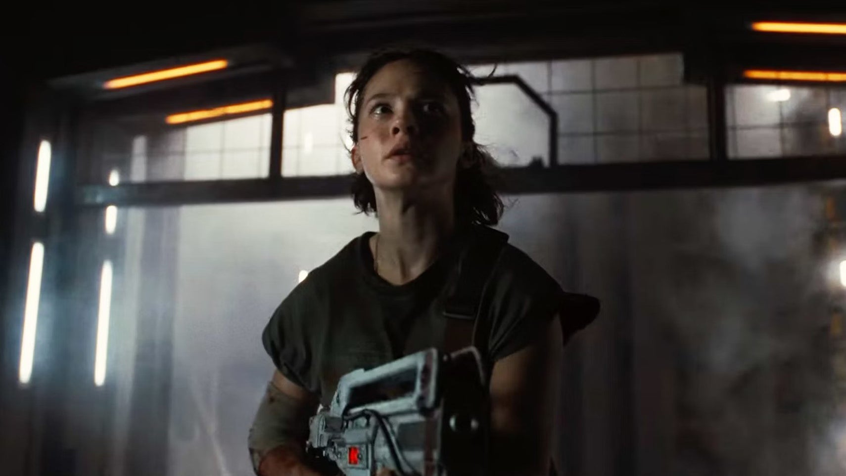 A still from Alien: Romulus showing a woman holding a sci-fi gun, she looks slightly scared. - 1