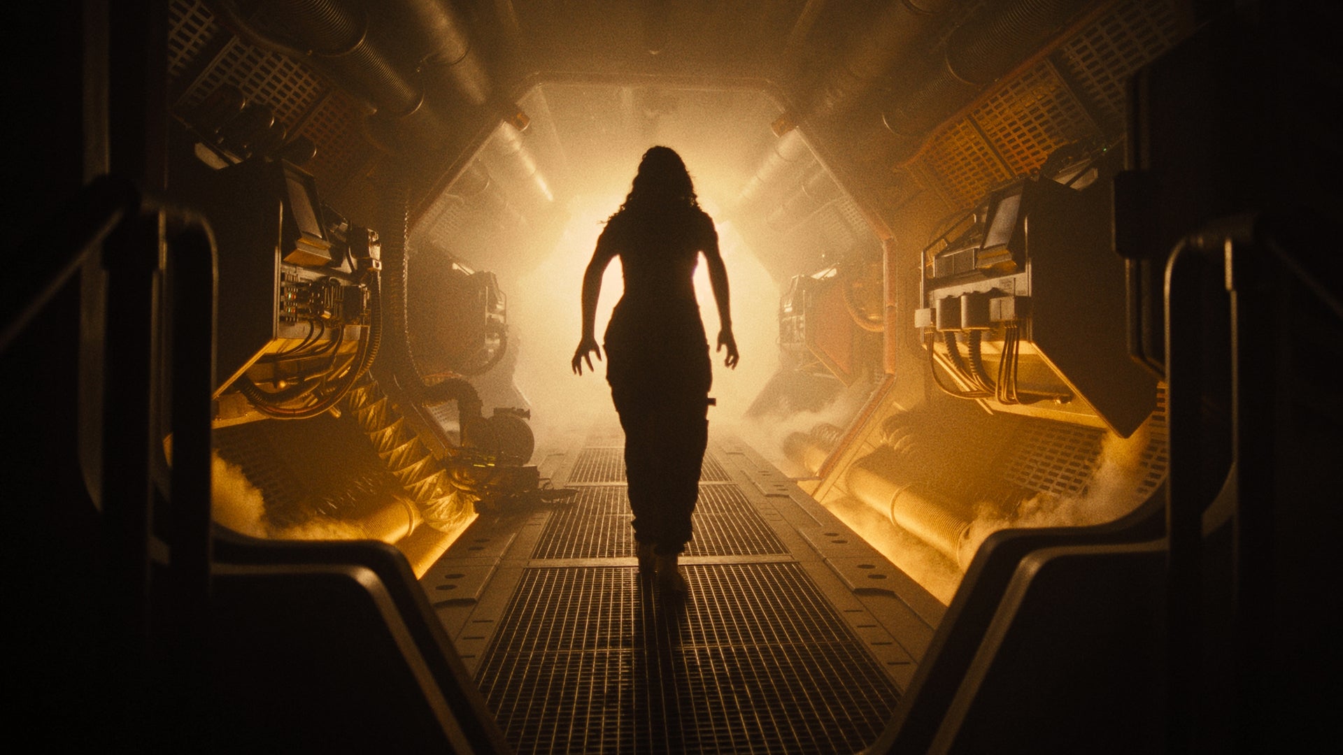Someone is stood in a sci-fi hallway, completely silhouetted by a foggy yellow light in Alien: Romulus.