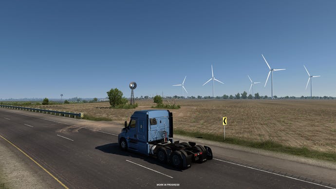 American Truck Simulator Texas - A truck cab drives down a two lane road with fields and wind turbines in the background.