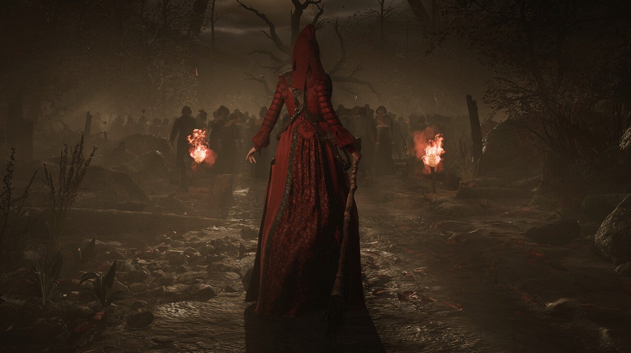 A woman in a red dress with her back to us, facing a torchlit group around a tree.
