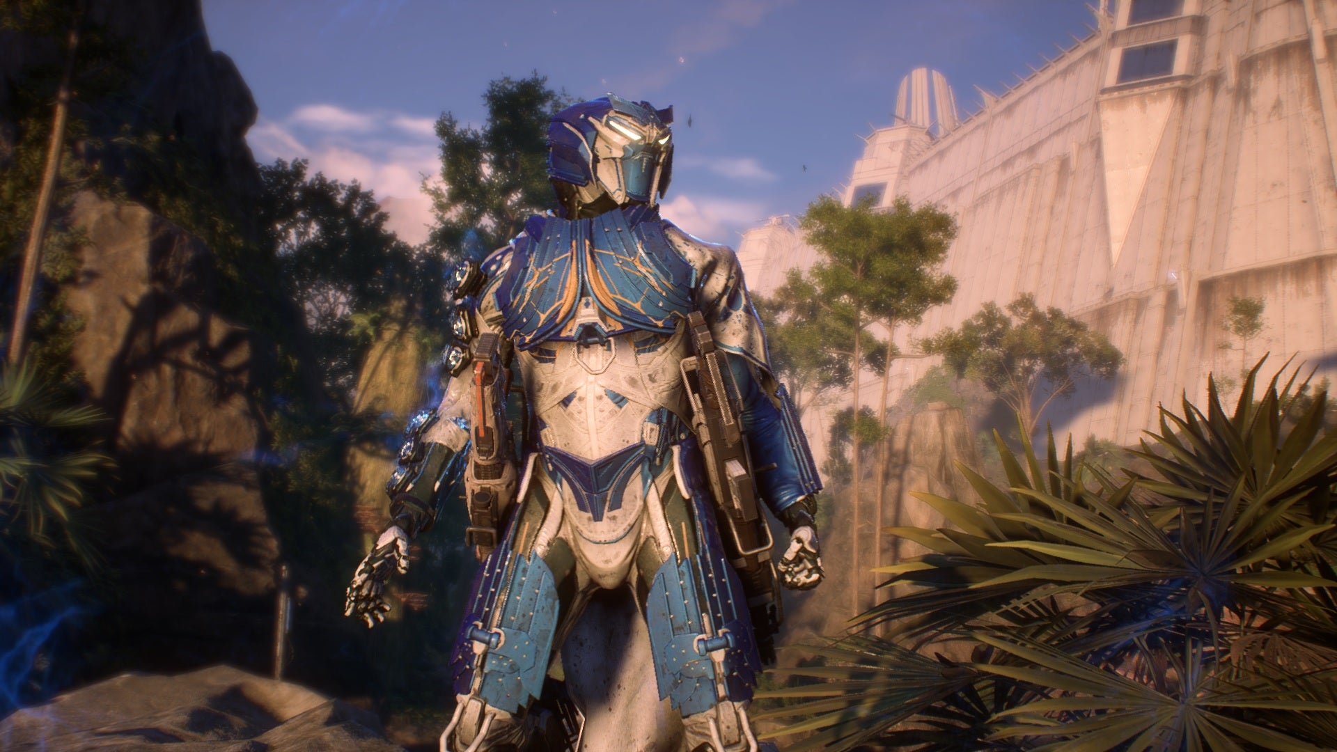 A character in their blue-white Javelin mech suit from Anthem, standing outside a huge fortress wall. - 1