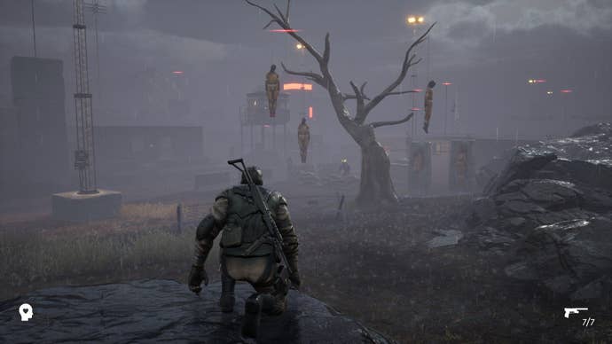 The hero crouches and looks at a tree in the misty distance, from which hangs three bodies in prison overalls.