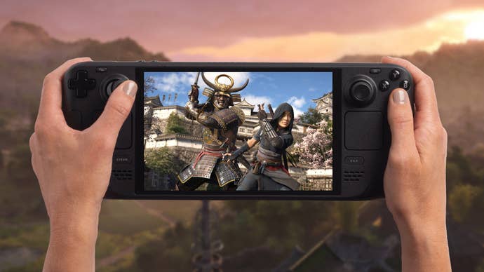 Mock-up of Assassin’s Creed Shadows running on a Steam Deck OLED. An in-game landscape viewed at sunset can be seen in the background.