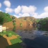 A screenshot of a river in Minecraft, with some trees on either side of the bank and a hill in the distance, taken using Astralex shaders.