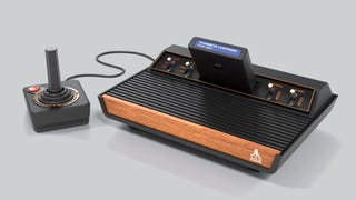 A picture of the Atari 2600+ console with a joystick attached and a 10-in-1 game cartridge plugged in. It has four-switches along the top edge of the console and a front plate with a wood-grain finish.