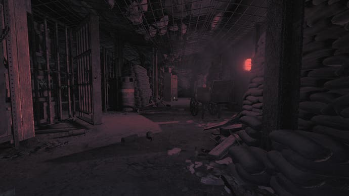 Amnesia: The Bunker review screenshot, where a red light casts a bloody sheen over sandbags, a gas canister, and scattered broken items on the floor.