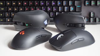 A photo of four wireless gaming mice in front of a keyboard