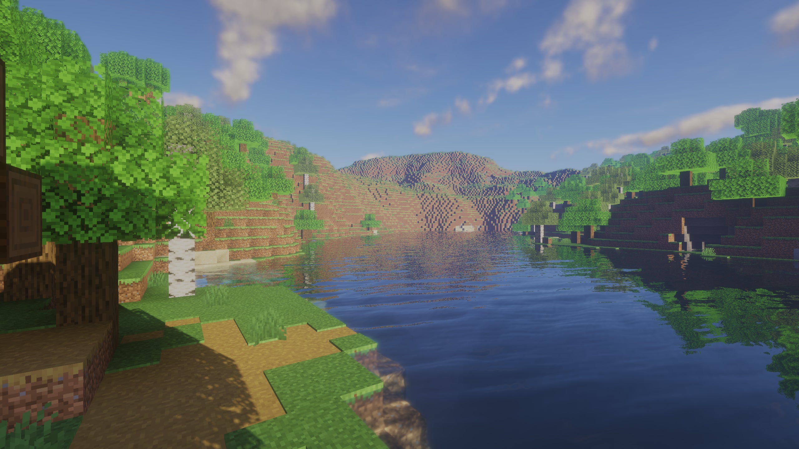 A screenshot of a river in Minecraft, with some trees on either side of the bank and a hill in the distance, taken using Beyond Belief shaders.