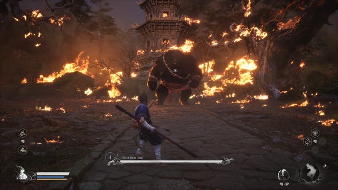 The player in Black Myth: Wukong prepares to fight Black Bear Guai, the main story boss of Chapter 1, against a backdrop of a burning temple village.