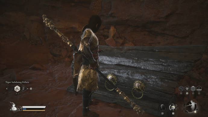 The player in Black Myth: Wukong opens a large wooden chest next to a cave wall.