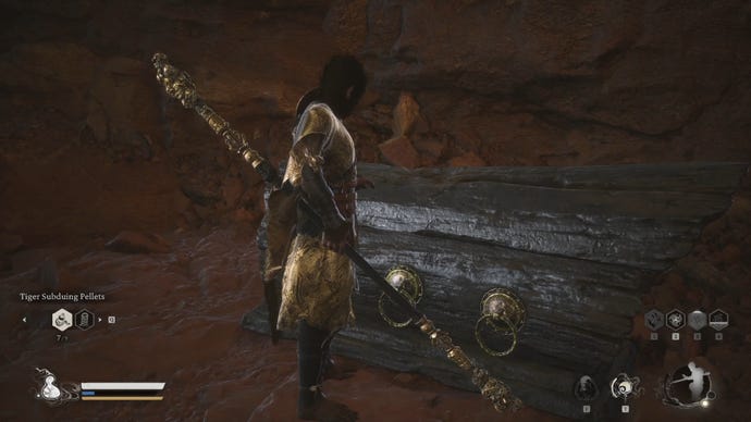 The player in Black Myth: Wukong opens a large wooden chest next to a cave wall.