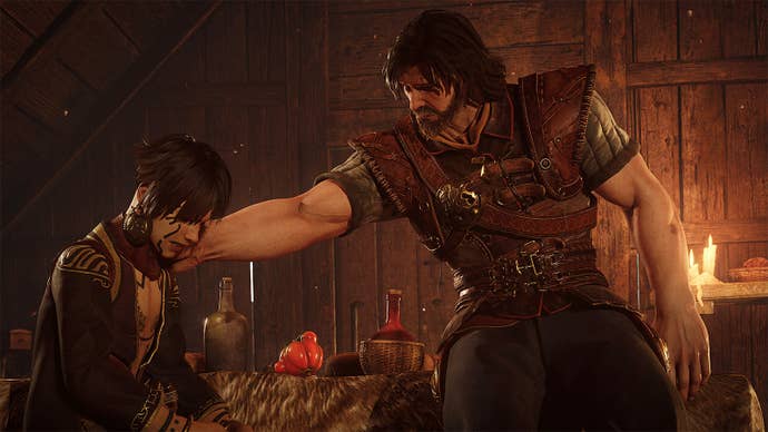 A bearded man with thick muscled arms comforts a young, tattooed person.