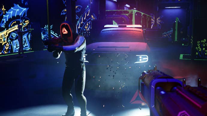A Blindfire screenshot showing a first-person view of a blacklit arena. Wall graffiti, a car, and another competitor are visible through the dark in splashes of neon.