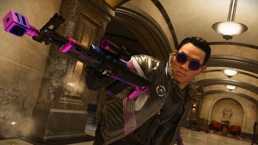 A guy wearing shades holds a rifle with one hand and aims it behind him.