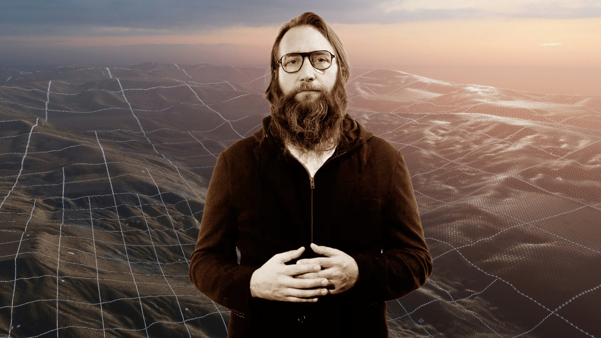 Brendan Greene stands with his hands clasped in front of a rolling digitised background landscape. - 1