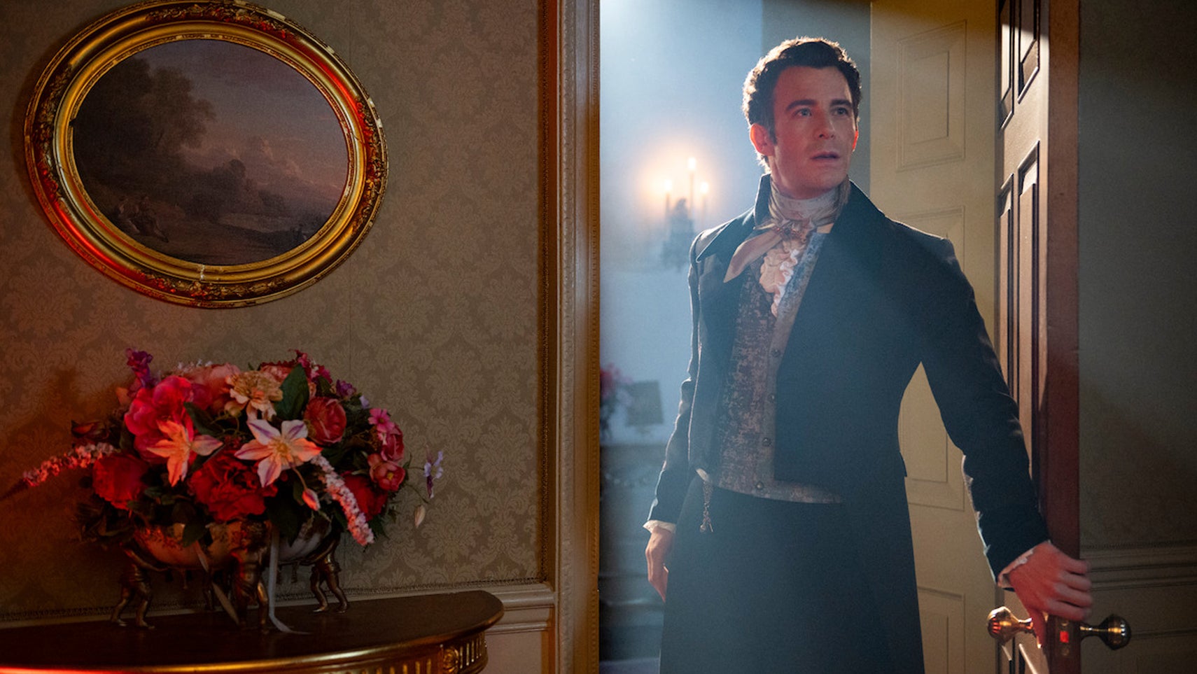 Benedict Bridgerton is stood in a doorway, light shining through it behind him, in a promotional image for Bridgerton. - 1