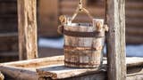 A photo of an old wooden bucket resting on top of an old well.
