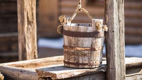 A photo of an old wooden bucket resting on top of an old well.