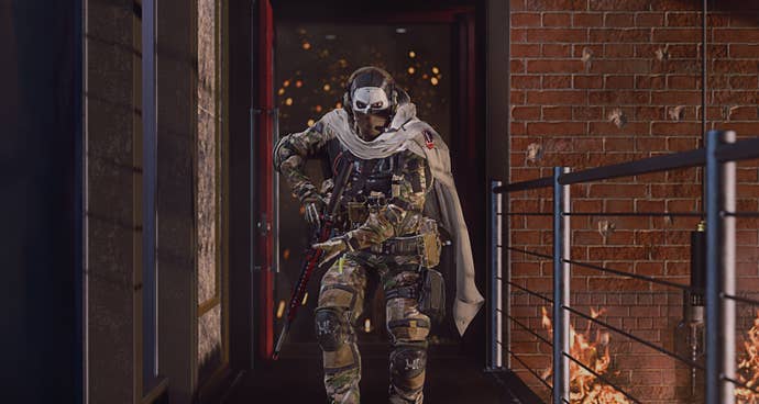 A soldier wearing a jaunty cape walks towards the camera on a platform underneath which the tops of flames are visible in Call Of Duty: Modern Warfare 2.