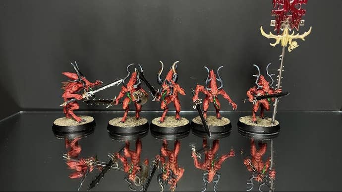 A group of four Bloodletter minifigs, one holding a banner that has extremely gooey looking blood on it