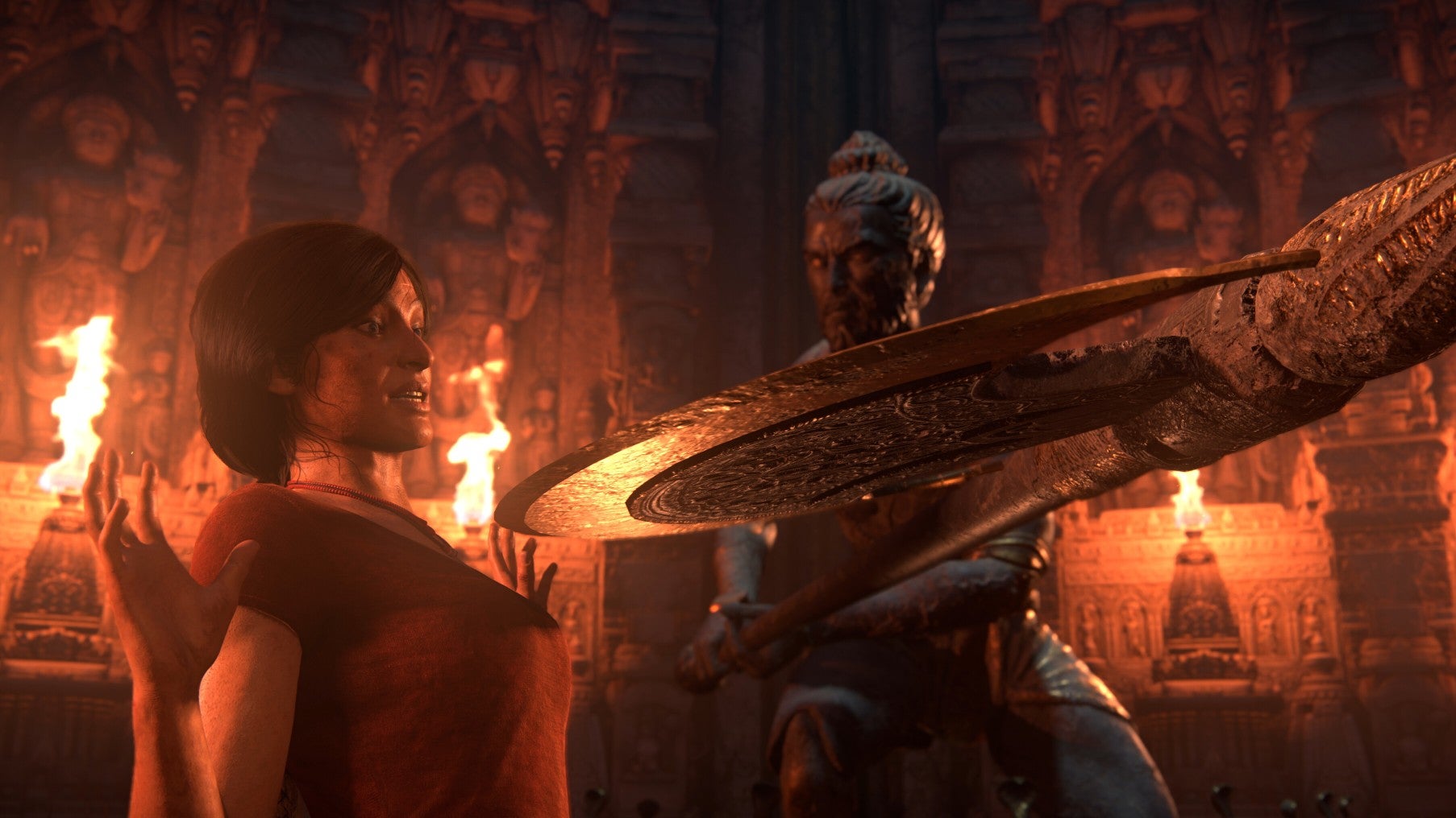 Chloe Frazer, wearing a red top, steps back with her arms raised as an axe swings down towards her