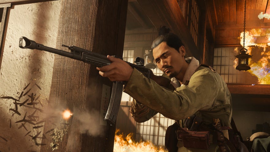 A player aims their rifle from the doorway of a burning building in Call Of Duty: Vanguard.