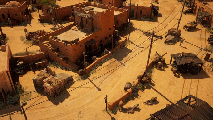 A Commandos: Origins screenshot showing an isometric view of German soldiers stationed around a town in the African desert while the titular commandos crawl along the ground behind a wall.