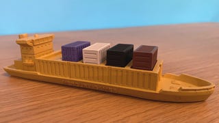 A huge board game piece from the game Container (Jumbo Edition). It is a container ship with removable shipping containers is in it.