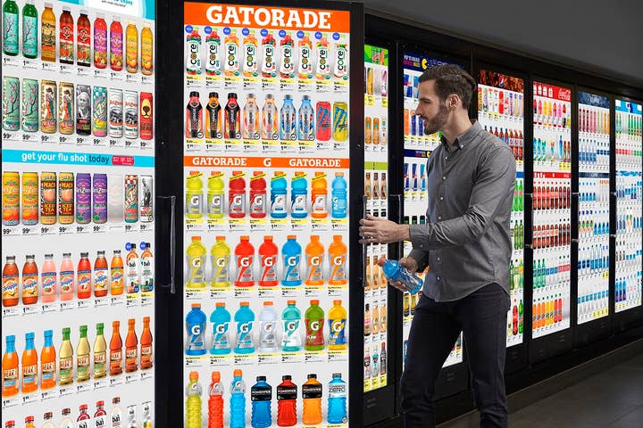 A man holds an open Cooler Screen door with one hand and a Gatorade bottle with the other. He is still peering into the cooler, as if there is something else in there that has grabbed his attention, perhaps beckoning him to venture into the cooler itself