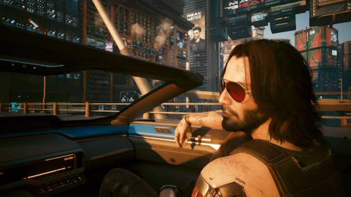 A screenshot from Cyberpunk 2077’s 2.2 update showing Johnny Silverhand riding through Night City in the passenger seat of a convertible car.