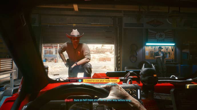 The player in Cyberpunk 2077 sits in the driver’s seat of their car in a garage. A sheriff stands at the front of the car, with one foot on the bonnet.