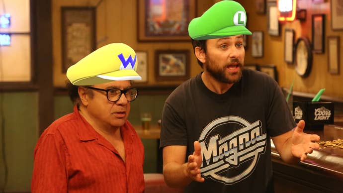 Danny DeVito and Charlie Day in Always Sunny in Philadelphia, they’re stood in a bar talking to someone offscreen, Wario and Luigi hats Photoshopped into their respective heads.