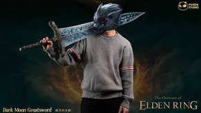 Person in grey jumped holding replica of Dark Moon Greatsword, large blue sword from Elden Ring, with a wolf image over the face