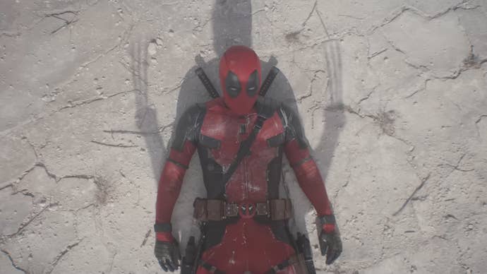 Deadpool is laying on the ground, looking up at Wolverine, who’s shadow can be see over Deadpool.