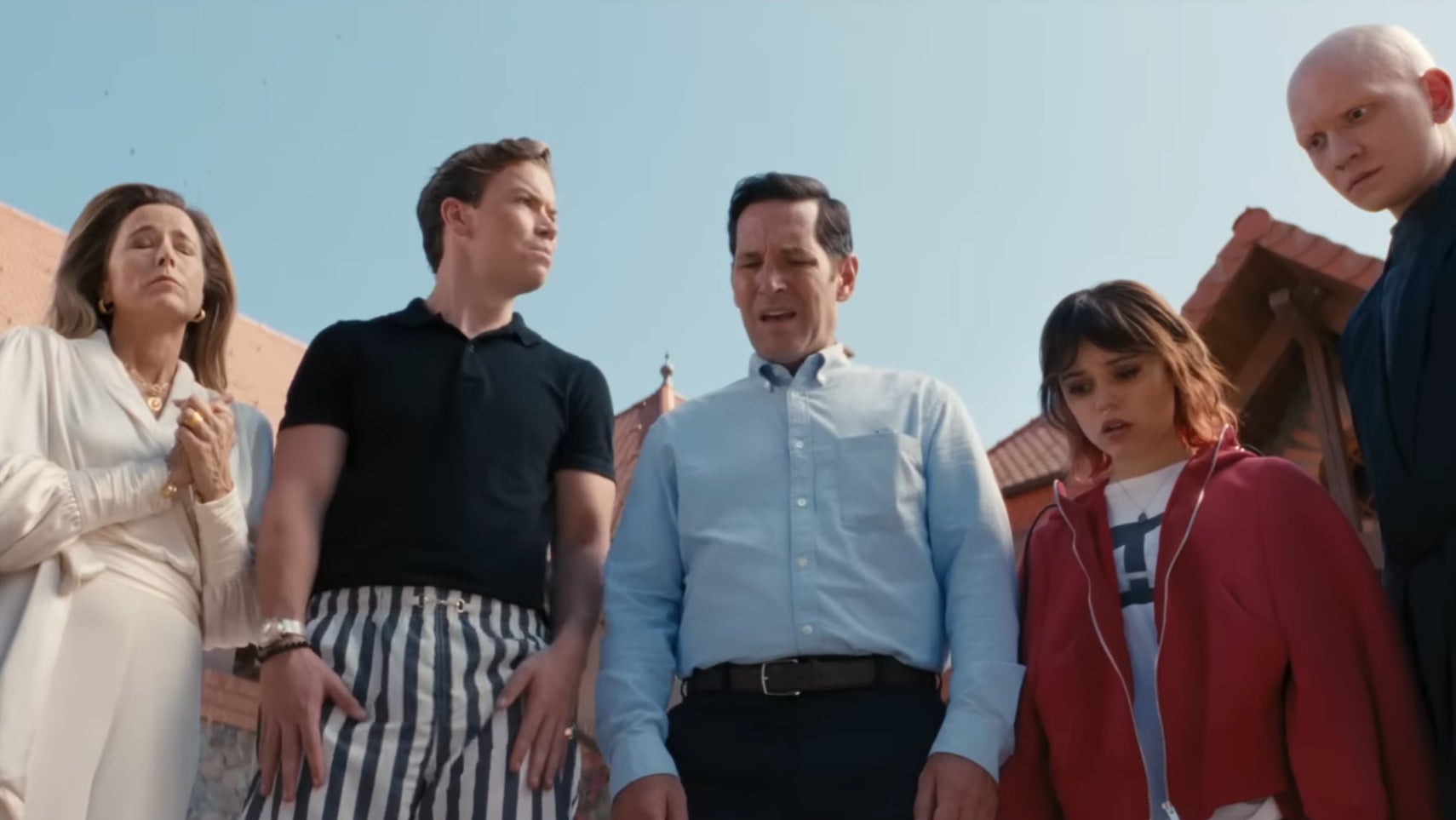 A group of people, including Paul Rudd and Jenna Ortega, are gathered around something, looking concerned at it, in Death of a Unicorn. - 1