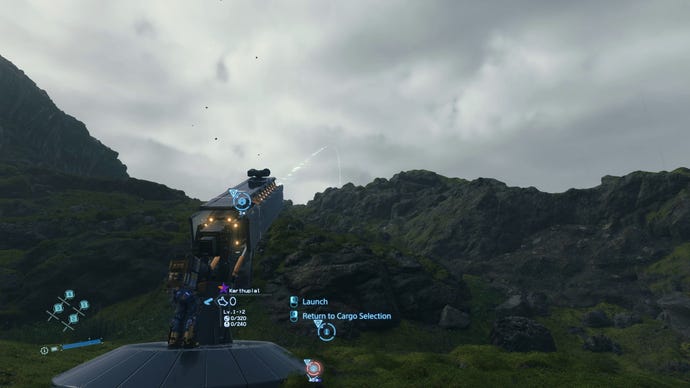 Sam prepares the new cargo catapult to fire some packages over a rocky mountain line in Death Stranding Director’s Cut