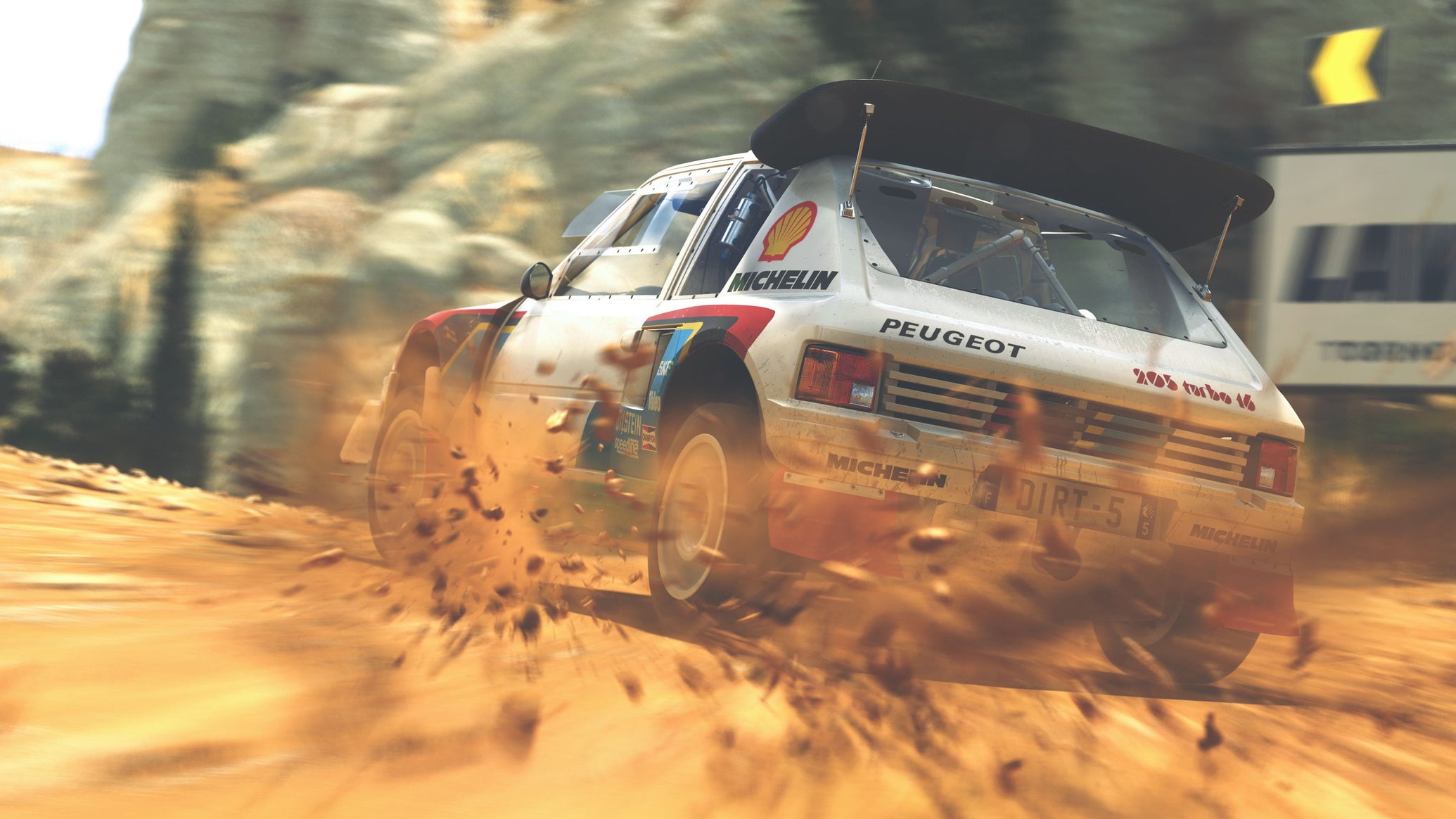 A rally car from Dirt 5 drifts around a corner in the sand. - 1