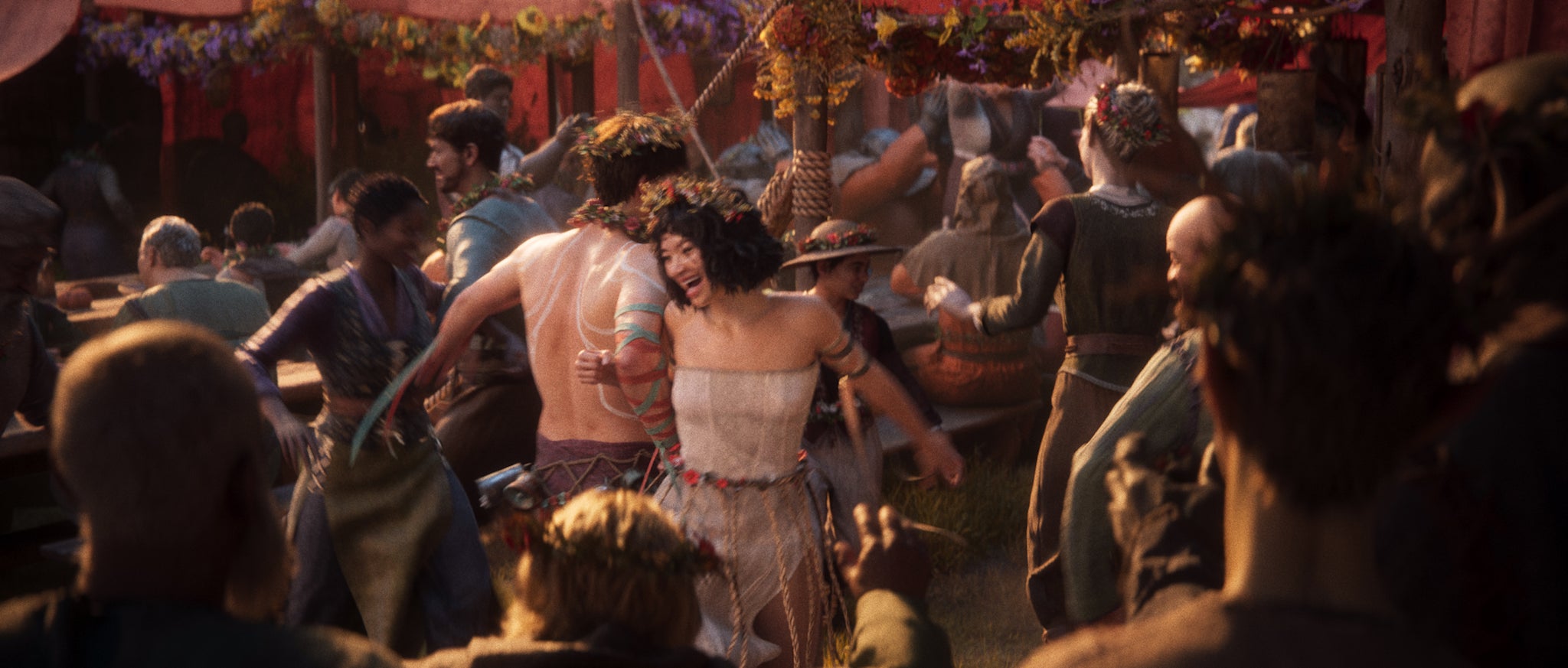 People dancing with floral wreaths at a drunken festival from the new Divinity game.