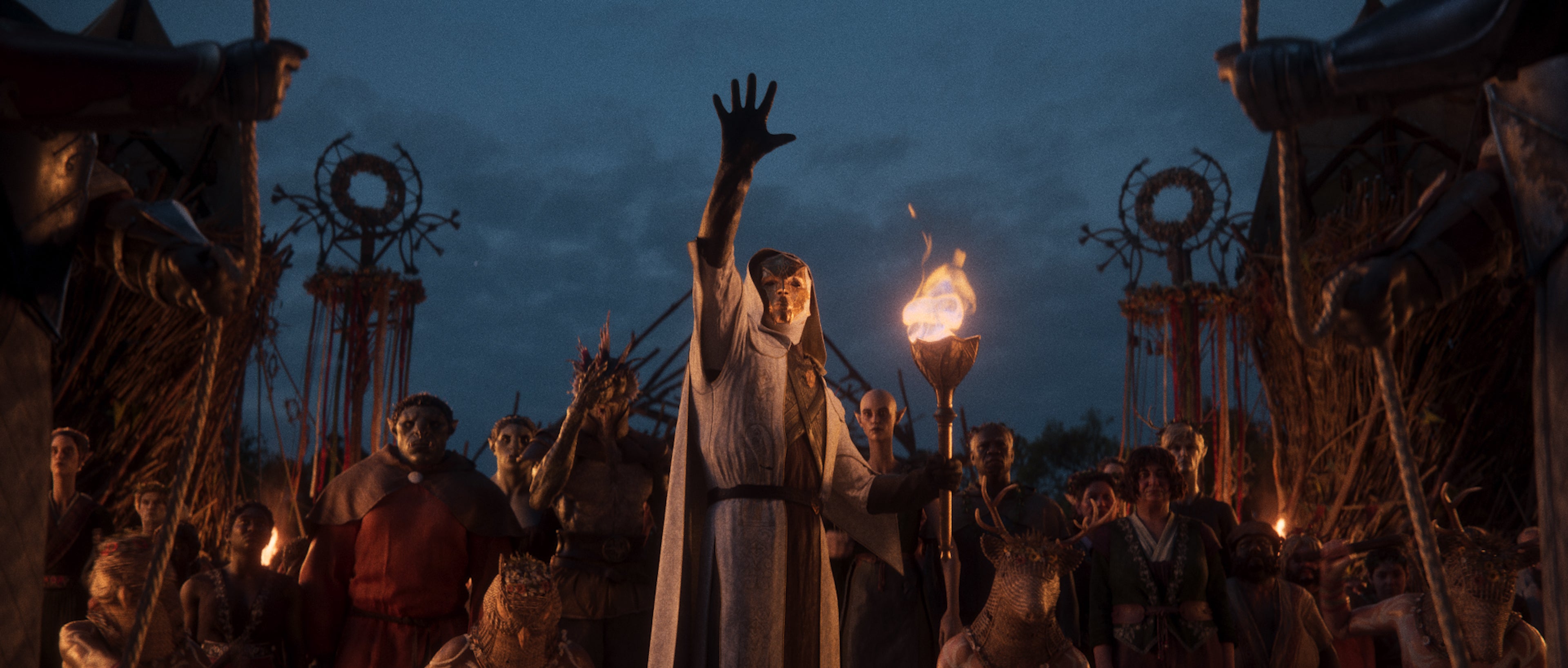 A view of a masked person in robes gesturing upward with a crowd gathered behind him, from a scene in the new Divinity RPG. - 8