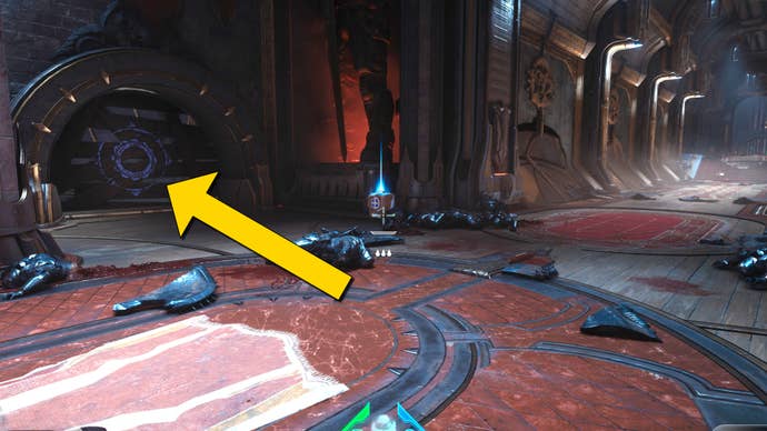 The player in Doom: The Dark Ages stands at the beginning of a long corridor near the start of Chapter 4. A yellow arrow points towards a section of breakable wall to the left which leads to the level's first secret area.