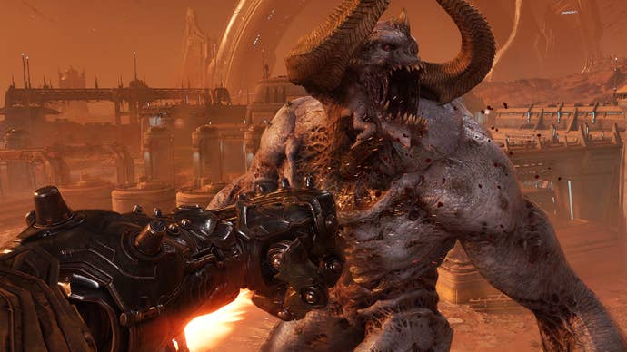 A Doom The Dark Ages screenshot showing a section of Atlan mech gameplay. A colossal armoured fist thumps the face of a colossal unarmoured demon. Chunks of flesh have been battered off of the thing. It probably deserved it.