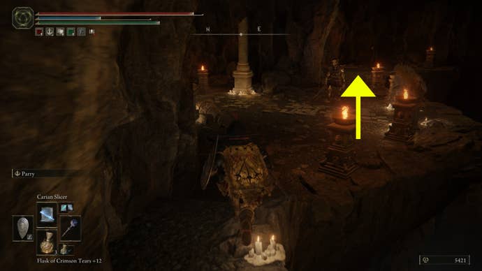 A screenshot with a yellow arrow past a skeletal enemy, showing where to go in the Dragon’s Pit dungeon in Elden Ring: Shadow of the Erdtree.
